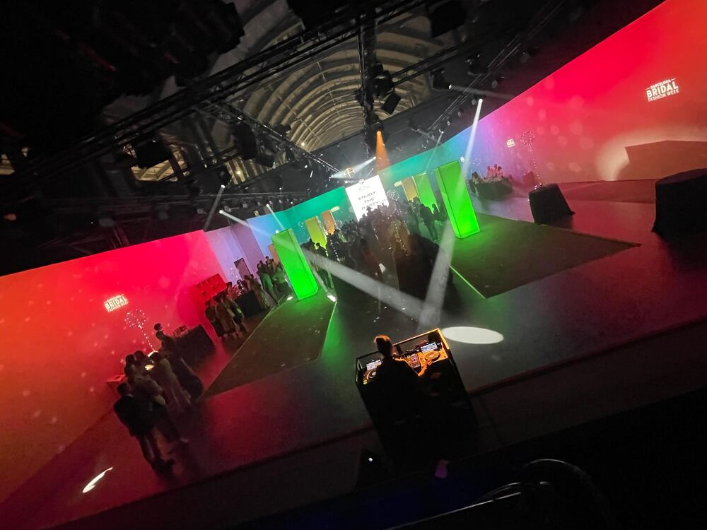 Pista de baile con iluminación de colores y cabina de DJ en un evento en nave